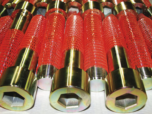 sonderschrauben-spezialschrauben-05-warmformteile-schmiedeteile-06 Metallrohre mit rotem Schutznetz, hexagonales Ende, in Reihe angeordnet (Industriekomponenten).