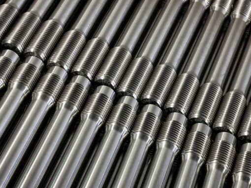 sonderschrauben-spezialschrauben-09-schraubenbolzen-01 Nahaufnahme von mehreren parallelen, silbernen Metallstangen mit Gewinde.