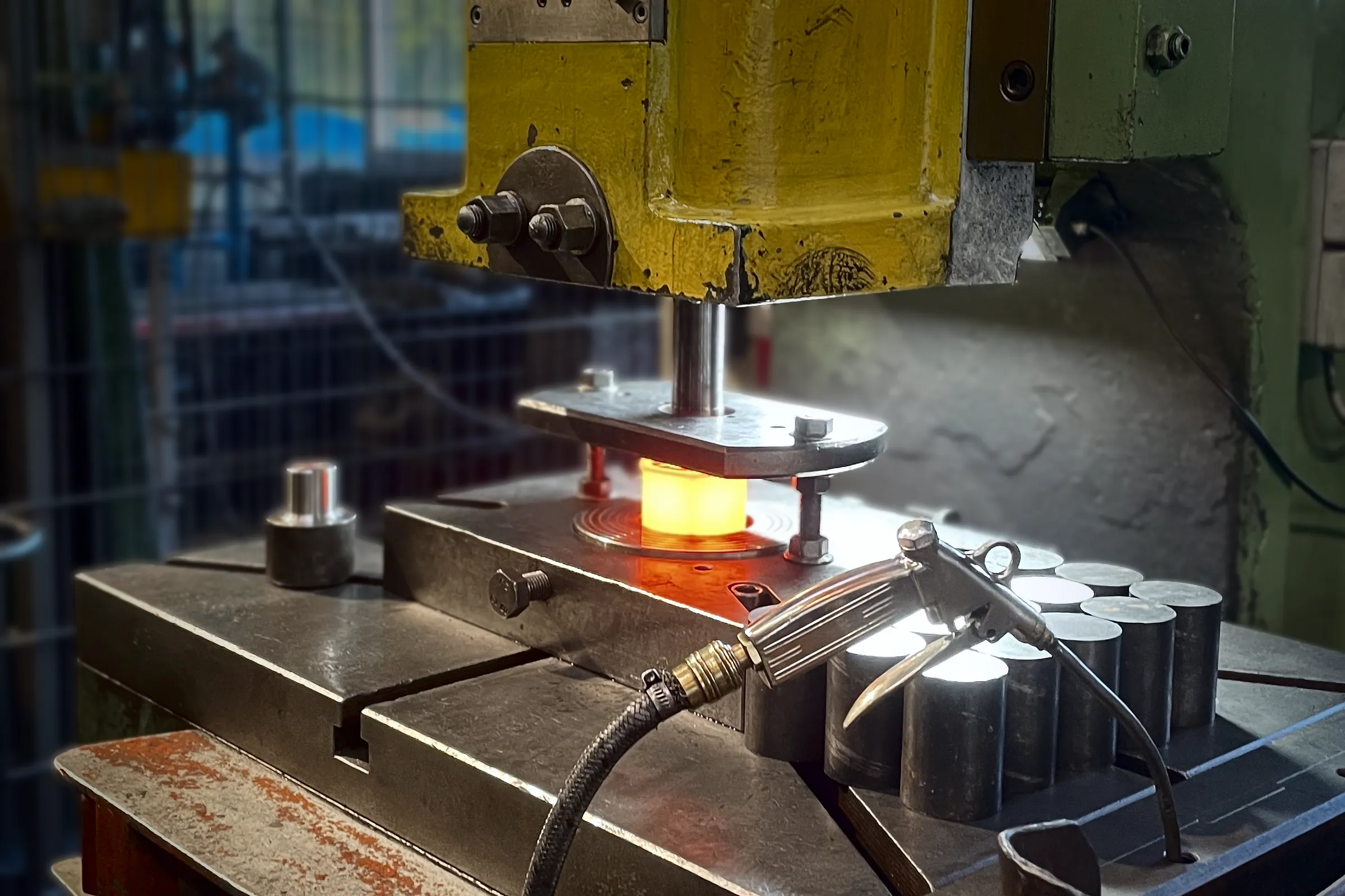Red-hot nut blank being pierced in the press